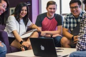 HSU students smiling and  watching video on Mac laptop